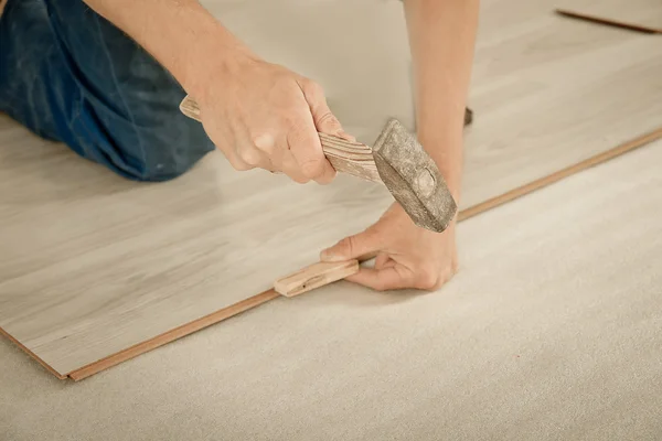 Man puts laminate — Stock Photo, Image