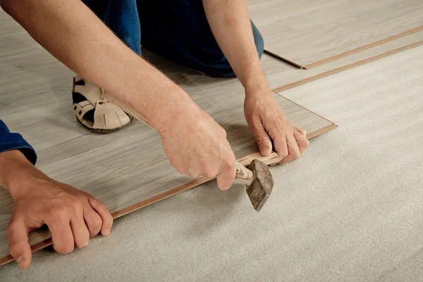 Man puts laminate — Stock Photo, Image