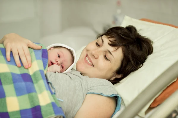 Mujer feliz después del nacimiento con un bebé recién nacido — Foto de Stock