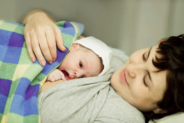 happy woman after birth with a newborn baby