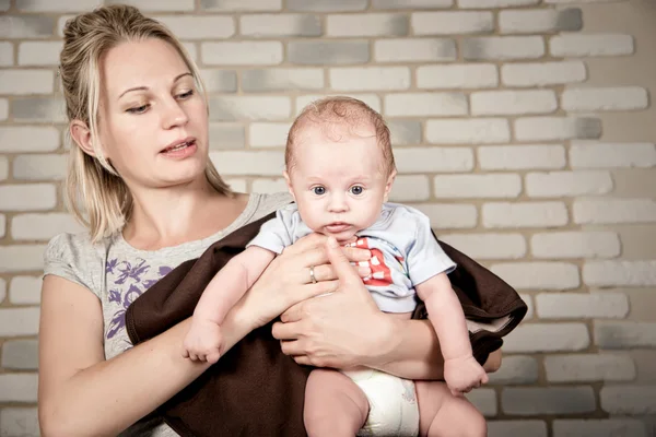 Hermosa mujer con un bebé en sus brazos, foto de estudio —  Fotos de Stock