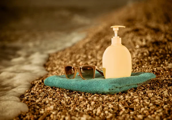 Towel, sunglasses and cream on the beach — Stok fotoğraf