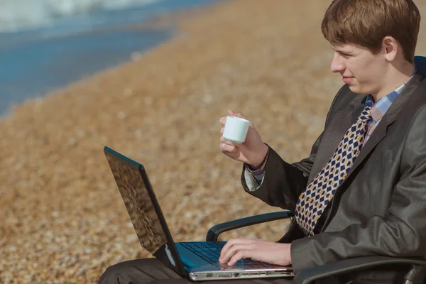 Jonge zakenman met een kopje koffie in een stoel van het Bureau op de — Stockfoto