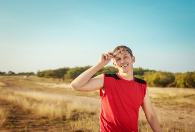 Young handsome man riding a bicycle in the field on a background of blue sky