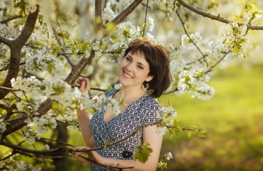 Young beautiful happy girl in the flowered garden