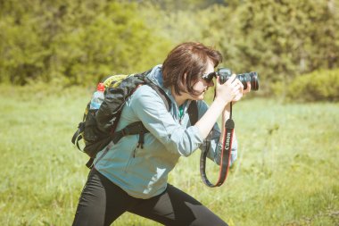 Girl tourist with a camera in the forest