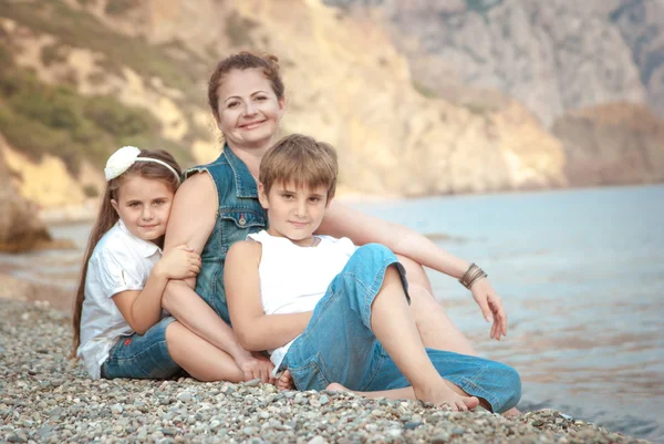 Young beautiful woman with a child on the beach — Stockfoto