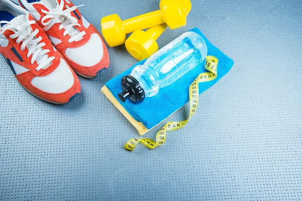 Zapatillas y pesas fitness sobre fondo gris. diferentes instrumentos para el deporte —  Fotos de Stock