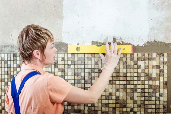 Laying ceramic tiles of the mosaic. Yellow line level for repairs. — Stock Photo, Image