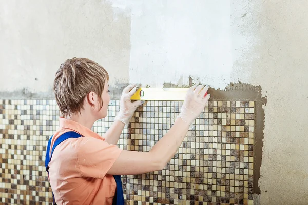 Verlegen von Keramikfliesen des Mosaiks. Gelbe Leitungsebene für Reparaturen. — Stockfoto