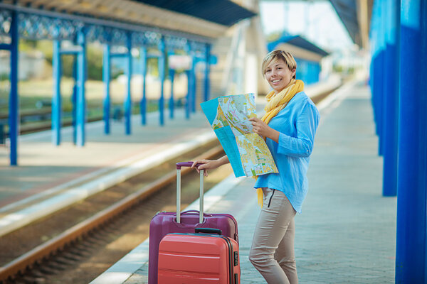 Девушка с чемоданом ждет поезд на вокзале Лицензионные Стоковые Фото