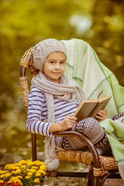 Kız açık havada bir kitap okuma. Dinlenme sonbahar parkta oturan çocuk — Stok fotoğraf