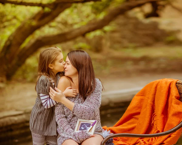 Parkta kızı rahatlatıcı ile hamile kadın — Stok fotoğraf