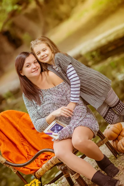 Беременная женщина с дочерью отдыхает в парке — стоковое фото