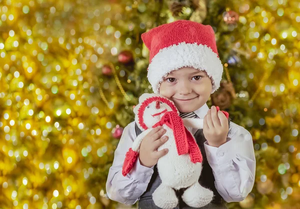 Menino em um chapéu de Papai Noel com um presente — Fotografia de Stock
