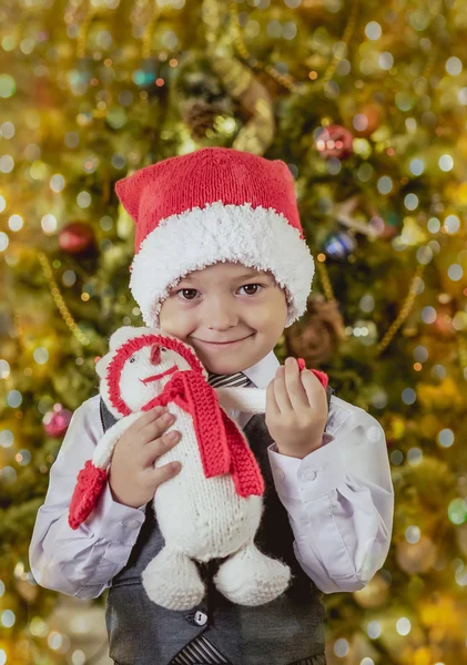 Menino em um chapéu de Papai Noel com um presente — Fotografia de Stock