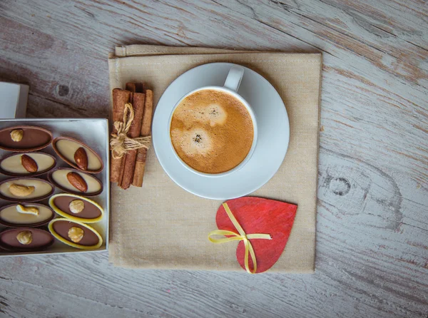 Šálek kávy s čokoládové bonbóny a skořicí — Stock fotografie