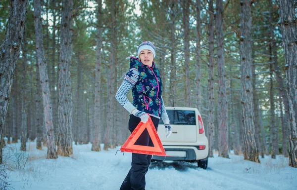 Route d'hiver. fille avec un triangle d'avertissement sur une route d'hiver — Photo