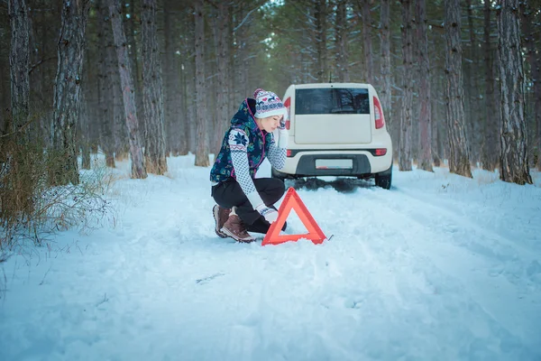 Зимняя дорога. девушка с предупреждающим треугольником на зимней дороге — стоковое фото