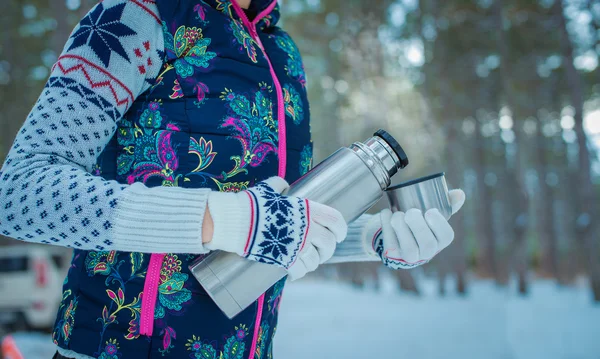 Mains de femme avec thermos sur fond d'hiver — Photo