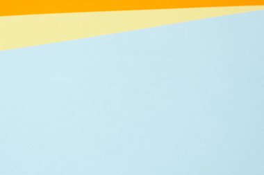 Colorful paper geometry background with blue, yellow, orange colors. Top view.
