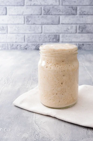 Fresh whole grain wheat sourdough in a glass jar for homemade bread or pizza.