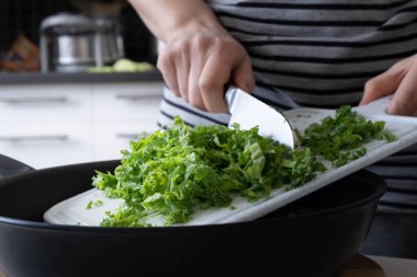 Kadın mutfakta lahana kesiyor.