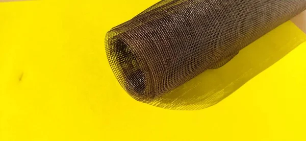 Rulla fönsterskärmen, närbild. Rulle med bruna myggnät. Störningsnät. Grid på gul bakgrund — Stockfoto