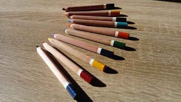 På ett träbord finns flera träfärgade pennor. — Stockfoto