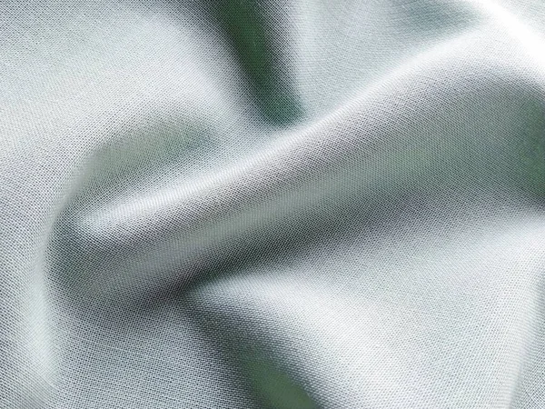 Beautifully folded light green fabric. Soft pleasant waves and flounces on textiles. Close-up. Drapery for curtains, fabric for dressmaking or upholstery.