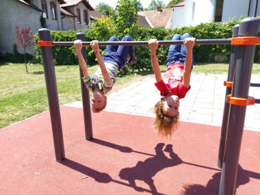 Sremska Mitrovica, Serbia. June 6, 2020. Flip-flops, weight lifting and weights, strength exercises. Two teenagers go in for sports on simulators, children on a sports ground. clipart
