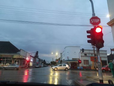 Trafik ışıkları ve trafik işaretleri olan bir cadde. Arabalar kavşağın önünde durur. Arabadan ateş etmek. Yağmurlu bir akşamda trafik vardı. Parlak trafik ışığı. Sremska Mitrovica, Sırbistan, 15 Ekim 2020
