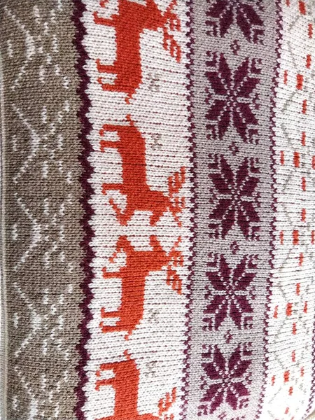 Knitted patterns with snowflakes, deer, flowers, broken stripes. Orange, red brown, white, beige woolen threads. Folk art. Warm winter sweater knitted with front loops. New Years and Christmas. — Stock Photo, Image