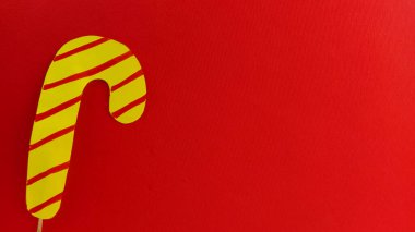 Kırmızı arka planda lolipop. Kırmızı çizgili sarı şekerin taklidi. Yeni yıl ya da Noel süsü. Uzayı kopyala Pankart.