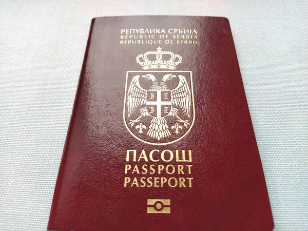 セルビアのパスポート 国境を越えるための新しい生体認証文書 公式文書だ 赤とバーガンディのパスポートは光沢のある文字でクラストします パスポートの表面は光を反射します — ストック写真