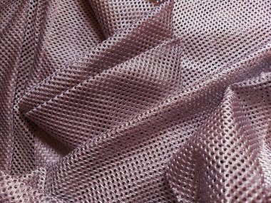 Delikli sentetik polyester kumaş. Soyut arkaplan. El sallayarak katlanmış pembe kumaş. Mobilya döşemesi.