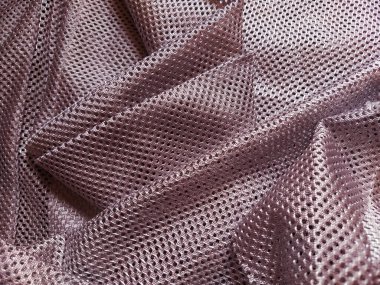 Synthetic polyester fabric with holes. Abstract background. Wave-folded pink fabric. Furniture upholstery. clipart