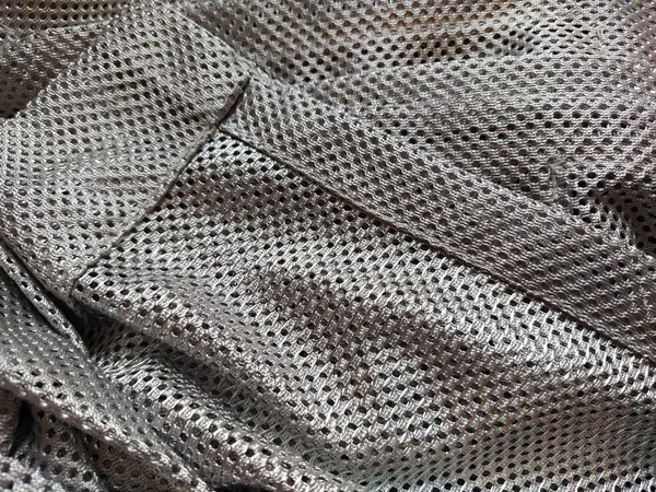 穴のある合成ポリエステル生地 抽象的な背景 灰色または銀色の布の波状の部分 素敵なヘミング生地 — ストック写真