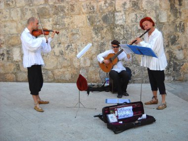 Dubrovnik, Dalmaçya, Hırvatistan, 5 Ağustos 2010. Sokak müzisyenleri müzik enstrümanları çalar. Geleneksel beyaz gömlekler, kırmızı bereliler. Dubrovnik Cumhuriyeti kostümü. Keman, gitar, pipo veya klarnet.