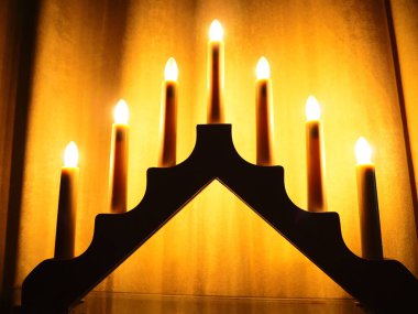 Schwibbogen kemeri, üçgen bir şamdan şeklinde. Sarı arka plan. Romantik, şenlikli, dini ya da mistik bir atmosfer. Mum ışığına benzeyen yanan ampuller, yumuşak odak.