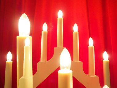 Schwibbogen kemeri, üçgen bir şamdan şeklinde. Kırmızı arka plan. Akşam, romantik, şenlikli, dini ya da mistik atmosfer. Yanan ampuller ya da mum ışığı. Çift pozlama