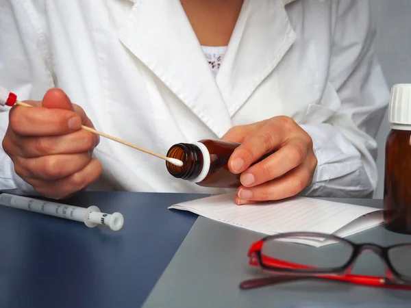 Corona virus test in the hands of a doctor. Doctor, nurse or laboratory assistant at work in the laboratory. On the table are glasses, measuring instruments, paper, medicines in bottles