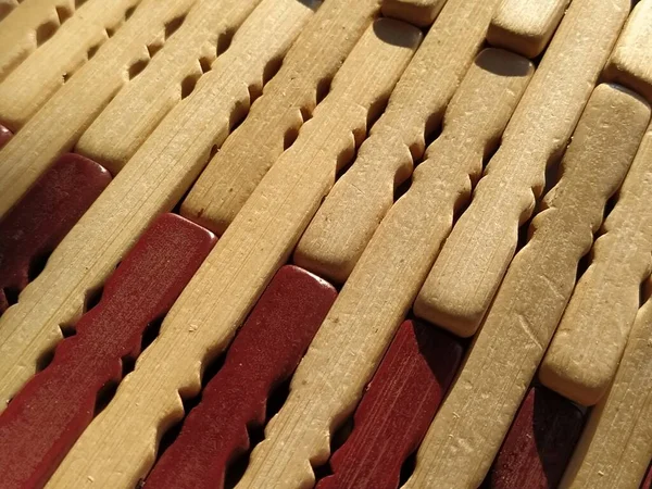 reed or wood mat. The rug is a mat under the hot. Knitted processed wood sticks with rounded edges. Close-up. Yellow, brown and beige colors. Side lighting. Traditional bamboo pad texture.