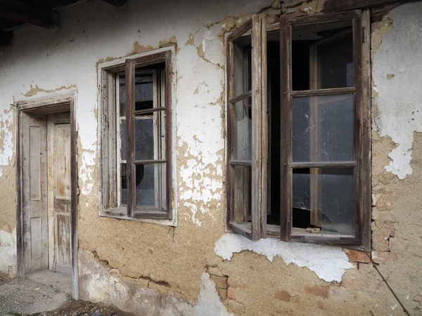 窓とドアのある古い家 田舎の家を崩壊させる 都市化と祖国の忘却の概念 放棄された家 窓にガラスが割れ 石膏が落ちる セルビアだ バルカン半島 — ストック写真