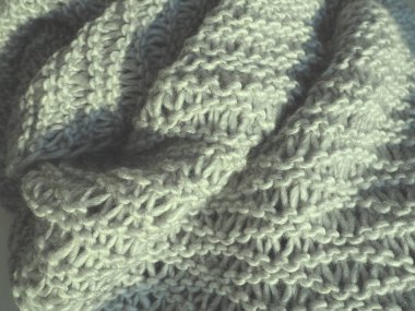 Gri iplikten örülmüş eşarp. Gür makine örgü örüyor. Sonbahar-kış dönemi için sıcak bir gardırop seçeneği. Öne dokuma, mor düğümler. Güzel ev hala hayat..