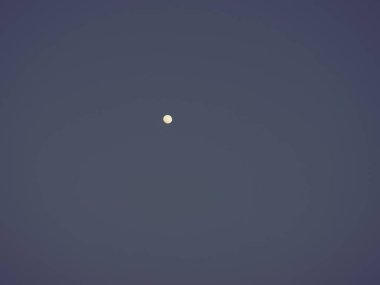 Gece mavi gökyüzünde ay. Gökyüzündeki beyaz nokta. Görüntünün kenarlarında koyu renk ağlar var.