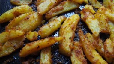 Kızarmış patates ya da zerdeçal, köri ve ekmek kırıntılarıyla patates kızartması. Yakın plan. Lezzetli meze. Fırın patatesleri. Latin Amerika ya da Belçika mutfağı. Fırından fırın tepsisi üzerinde yemek. Video