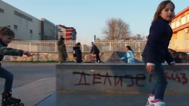 Un niño y una niña están patinando, conduciendo hacia una colina, un obstáculo. Ocio. Entrenamiento deportivo en el sitio. 7 de marzo de 2021 Sremska Mitrovica, Serbia. — Vídeo de stock