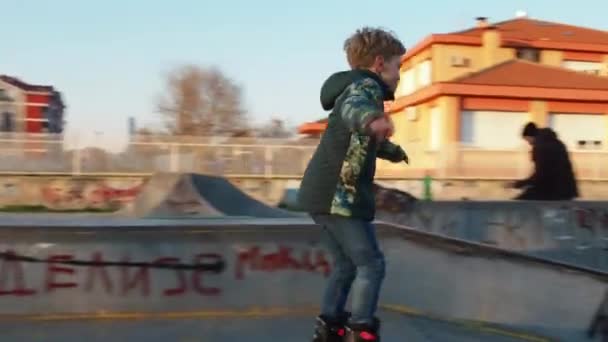 A boy and a girl are rollerblading, driving onto a hillock - an obstacle. Leisure. Sports training on the site. March 7, 2021 Sremska Mitrovica, Serbia. People and cyclists. Slow motion — Stock Video