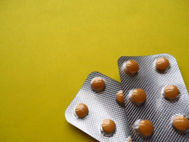 Sarı arka planda bir sürü hap. Hastalıkların tedavisi için kapsüllü haplar, vitaminler ve kabarcıklar. Boşluğu kopyala